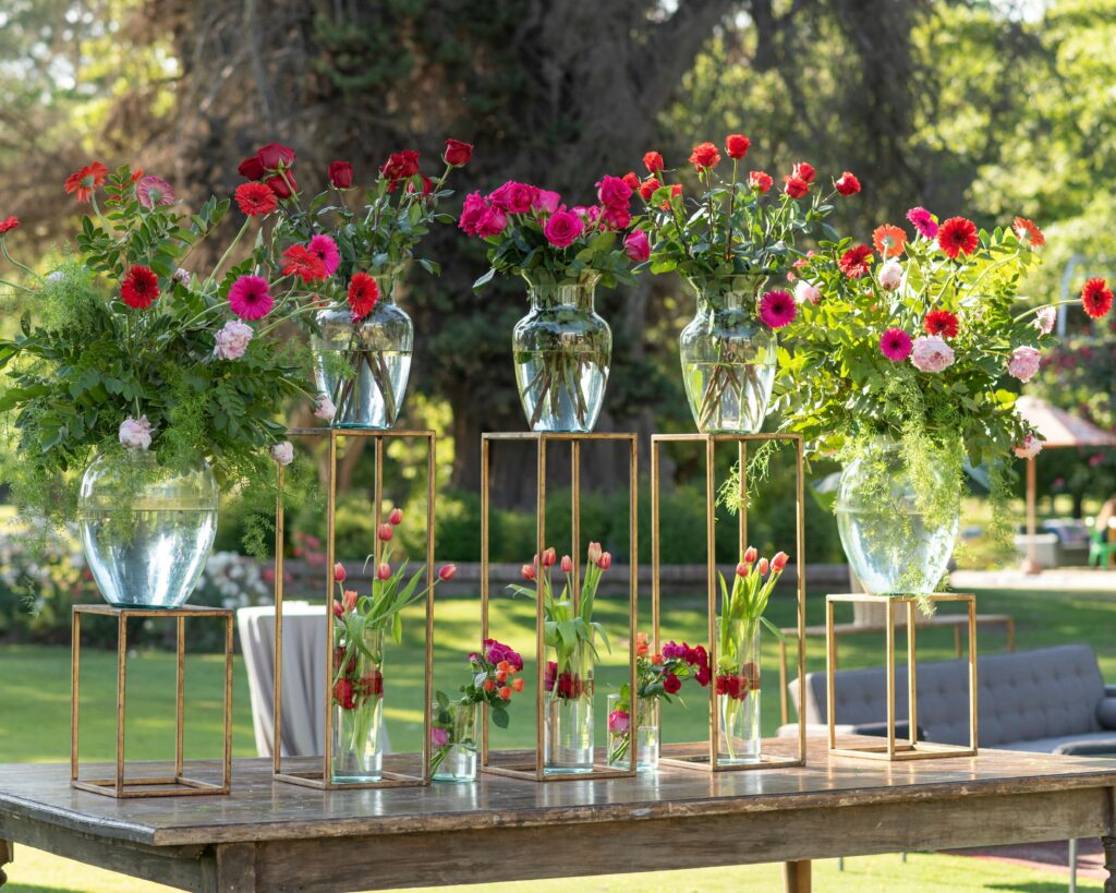 Beautiful outdoor floral arrangement with vibrant flowers on rustic table at a sunny event.
